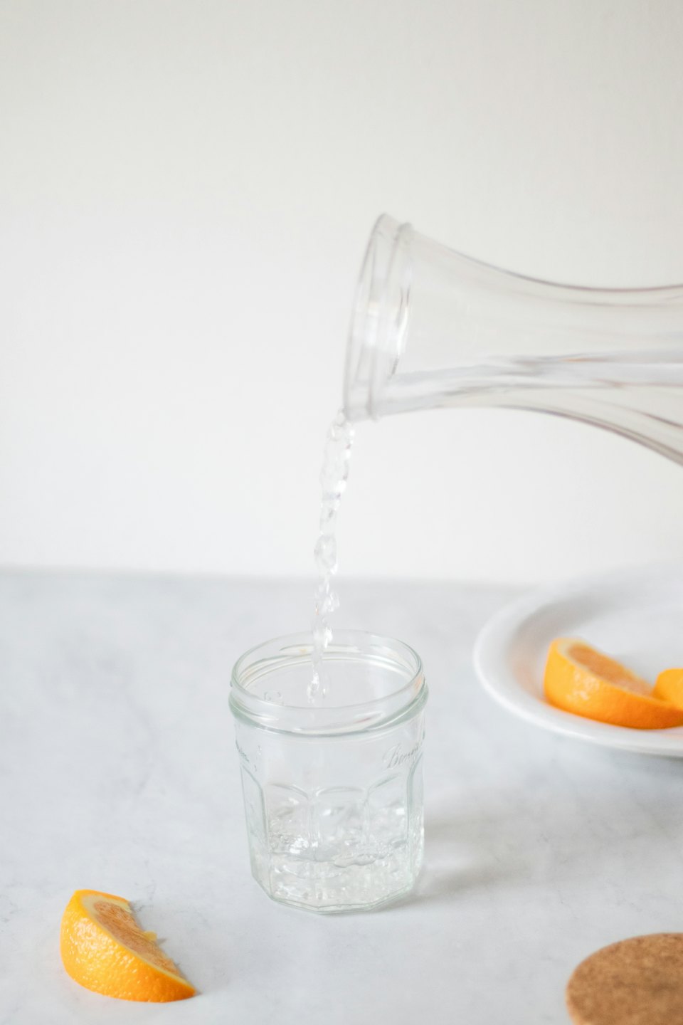 Clear water pours from a pitcher into a glass jar.