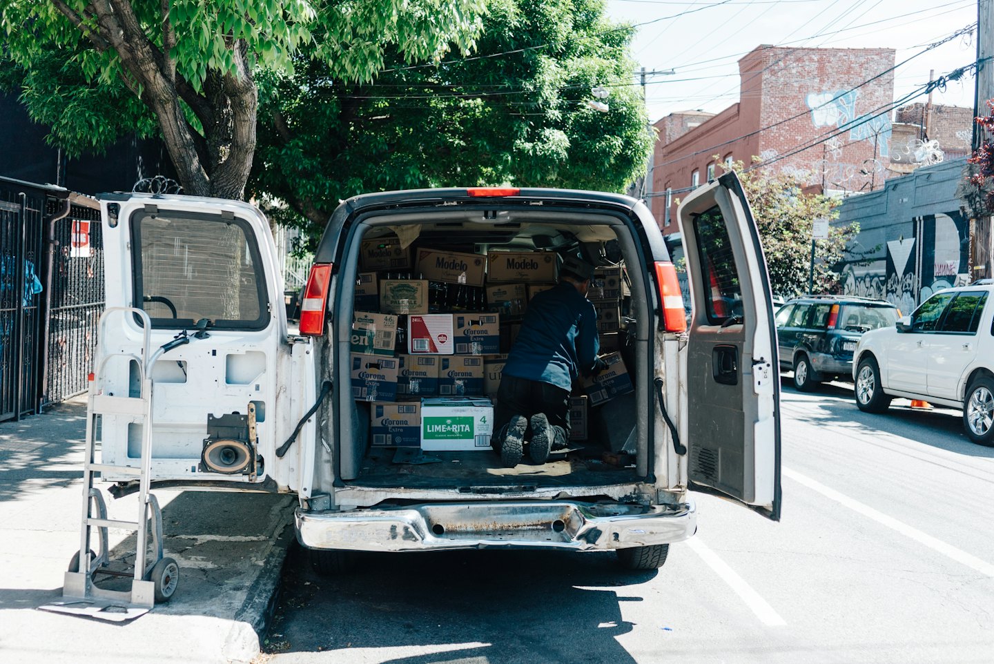 Delivery worker arranging boxes of beverages inside a van.